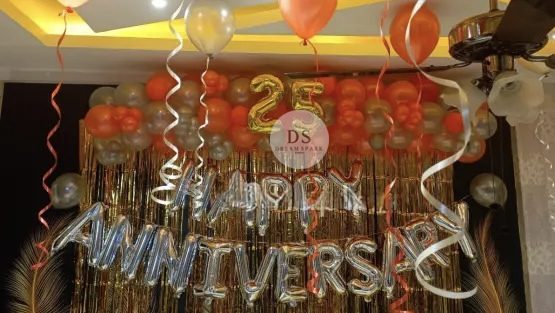 25th Anniversary Decoration Package 1 25th Anniversary Decoration Package featuring 90 gold, orange, and silver balloons with a golden backdrop and Happy Anniversary lettering by Dream Spark Events