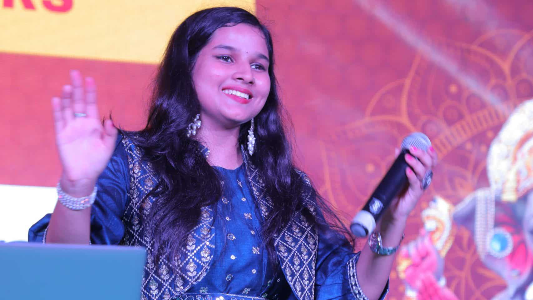 Woman speaking with microphone on stage - Khushi Singh